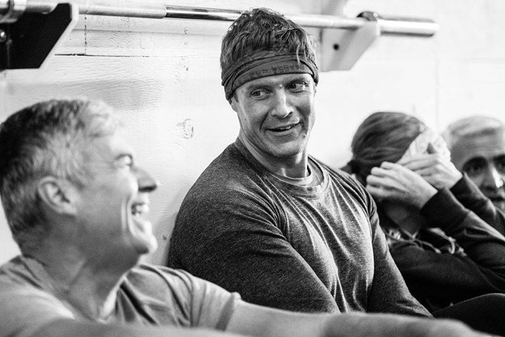 Dai Manuel talking with fellow gym participants in a black and white photograph