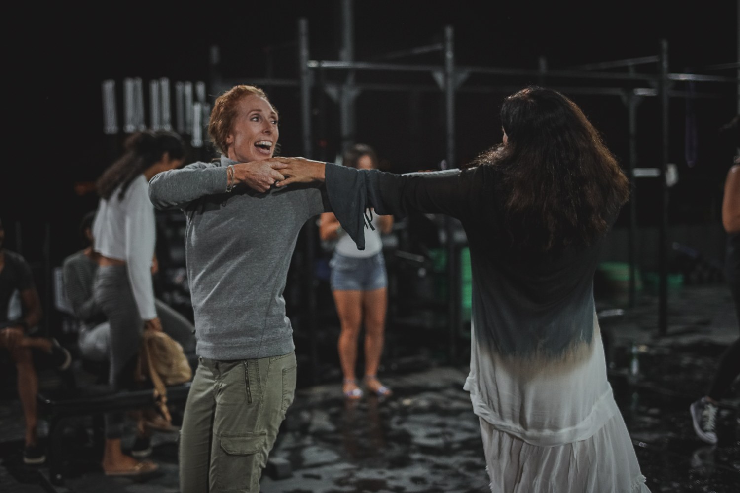 Two participants smiling during a partner exercise in a gym